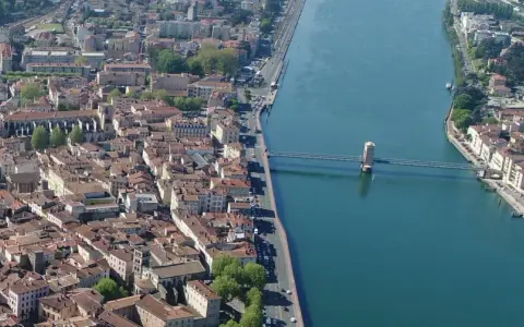 Vue aérienne de la ville de Vienne, traversée par un fleuve et un pont. L'école de Vienne se reflète dans l'eau.