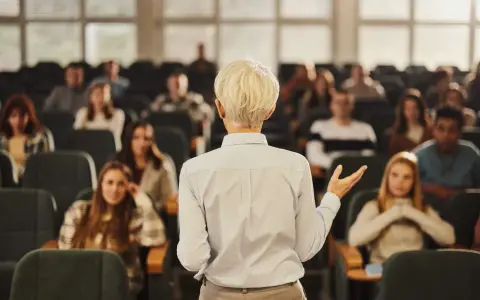 Professeure s'adressant à des étudiants dans un amphithéâtre, un lieu d'apprentissage pour une école de commerce publique gratuite.