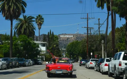 Voiture rouge décapotable, palmiers, panneau Hollywood. Le cout de la vie USA, un rêve pour certains, une réalité coûteuse pour d'autres.