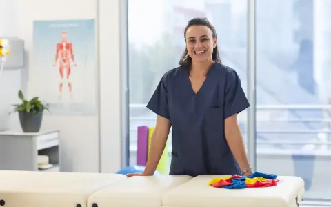 Une kinésithérapeute souriante dans sa salle de soins, prête à accueillir ses patients. L'école kine Saragosse forme des professionnels de santé.