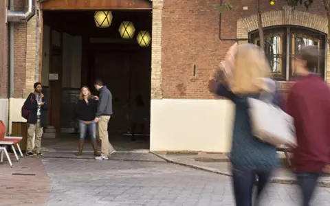 Des étudiants discutent dans une cour d'une vieille bâtisse, un lieu qui pourrait être un master à Madrid.