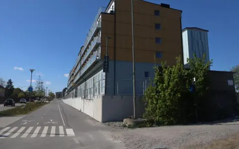 Immeuble moderne avec balcons vitrés, idéal pour le logement étudiant à Stockholm. Une piste cyclable longe le bâtiment.