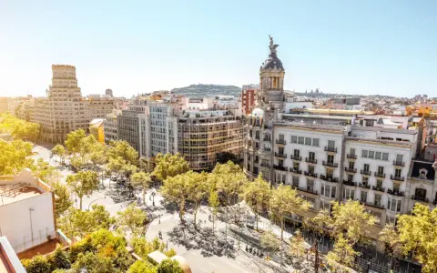 Vue aérienne de Barcelone, ville dynamique qui pourrait figurer dans le classement université espagne. Bâtiments haussmanniens, arbres luxuriants et ciel bleu.