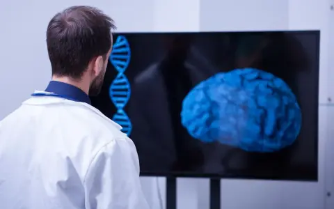 Un médecin observe un cerveau bleu et une double hélice sur un écran, signe d'une formation neuropsychologie à distance.