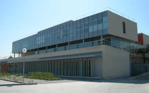 Bâtiment moderne aux lignes épurées, possiblement une école d'élite à Madrid, avec de grandes baies vitrées et une façade en pierre claire.