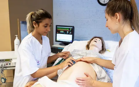 Étudiantes en sage-femme en Belgique pratiquant sur un mannequin de grossesse.