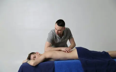 Un étudiant en école kiné Luxembourg pratique un massage du dos sur un patient.
