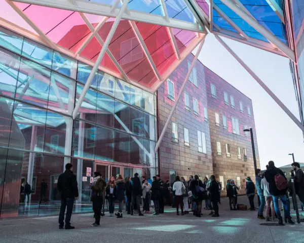 Étudiants devant le bâtiment moderne de l'ICN Business School, avec sa façade vitrée et son toit coloré.