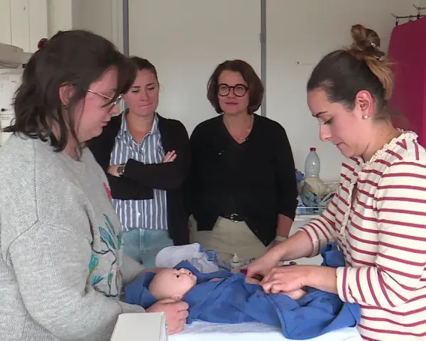 Des infirmières pédiatriques en formation observent et pratiquent les soins sur un poupon.