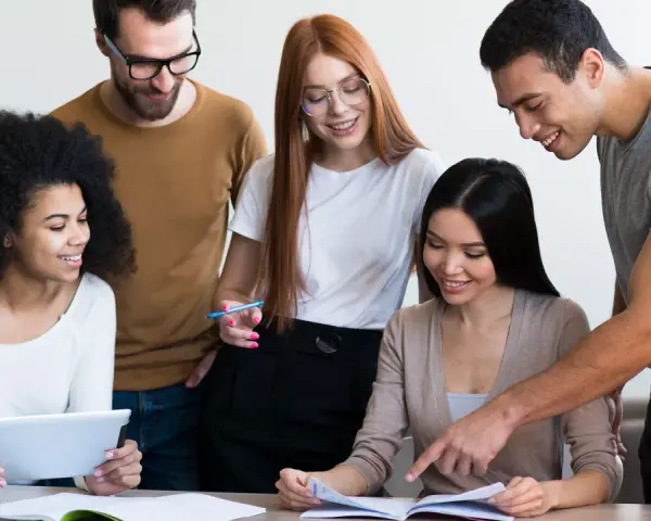Une équipe diversifiée collabore sur un projet, comme un master moyen orient. Ils étudient des documents et utilisent une tablette.