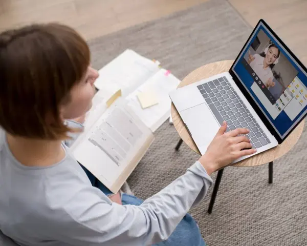 Étudiante en licence neurosciences à distance, elle étudie sur son ordinateur portable et des livres ouverts.