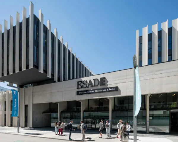 Devant l'ESADE Barcelone, une école reconnue pour son classement, des étudiants discutent sous un ciel bleu.