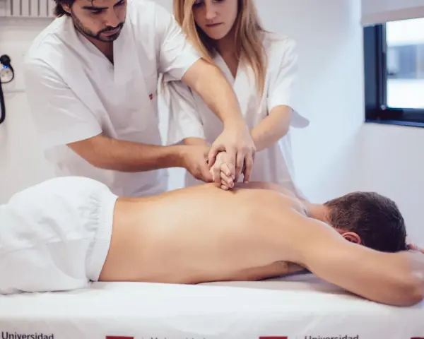 Des étudiants de l'école kine Gérone apprennent la kinésithérapie en pratiquant sur un patient allongé.