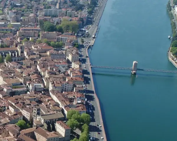 Vue aérienne de la ville de Vienne, traversée par un fleuve et un pont. L'école de Vienne se reflète dans l'eau.