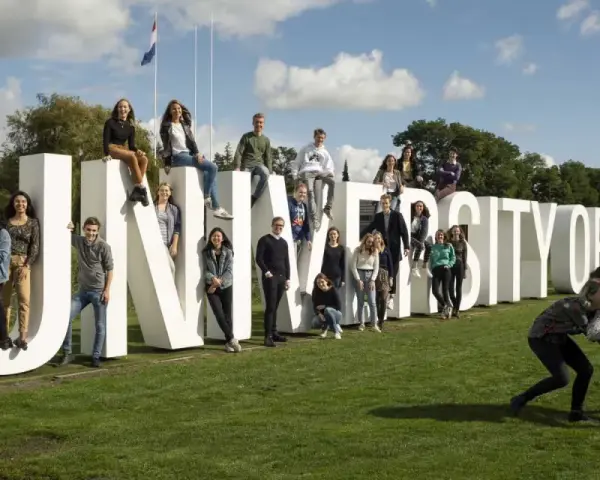 Un groupe d'étudiants pose joyeusement devant les lettres géantes "UNIVERSITY OF TWENTE".