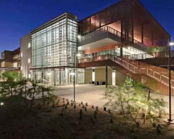 Bâtiment moderne d'un college aux États-Unis, avec une façade vitrée et des escaliers extérieurs en bois, éclairé la nuit.