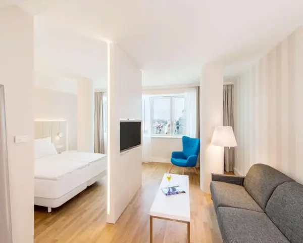 Chambre moderne avec lit, canapé, TV et vue sur la ville. Idéal pour un logement étudiant à Vienne, Autriche.