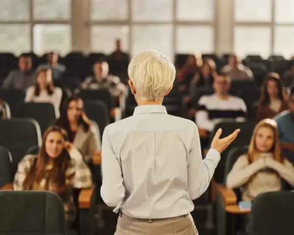 Professeure s'adressant à des étudiants dans un amphithéâtre, un lieu d'apprentissage pour une école de commerce publique gratuite.