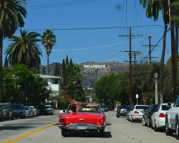 Voiture rouge décapotable, palmiers, panneau Hollywood. Le cout de la vie USA, un rêve pour certains, une réalité coûteuse pour d'autres.