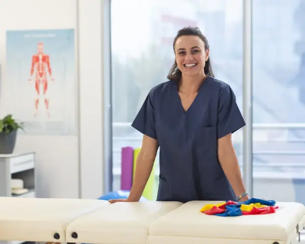 Une kinésithérapeute souriante dans sa salle de soins, prête à accueillir ses patients. L'école kine Saragosse forme des professionnels de santé.
