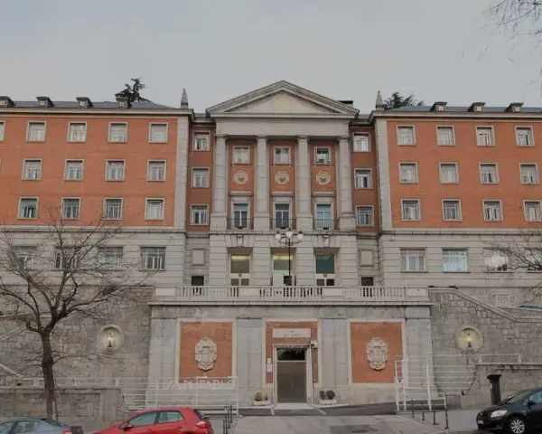Bâtiment en brique avec des colonnes, des fenêtres et un toit mansardé. Le nom "CEU San Pablo" est visible sur la façade.