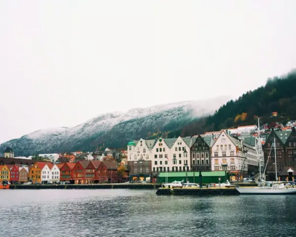 Vue du port de Bergen, Norvège, avec ses maisons colorées et ses montagnes enneigées. Un aperçu du coût de la vie en Norvège.