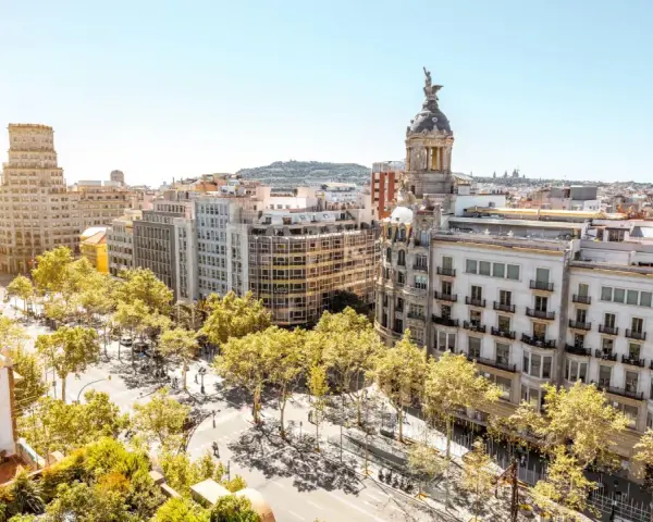 Vue aérienne de Barcelone, ville dynamique qui pourrait figurer dans le classement université espagne. Bâtiments haussmanniens, arbres luxuriants et ciel bleu.