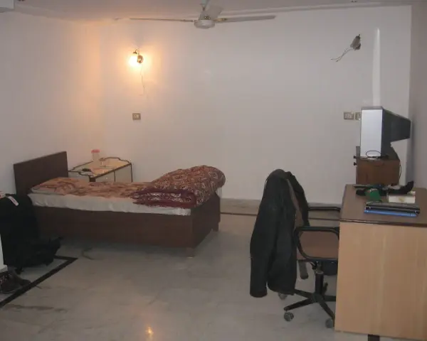 Chambre modeste en Inde, avec un lit, un bureau et une télévision. Un aperçu du cout de la vie en Inde.