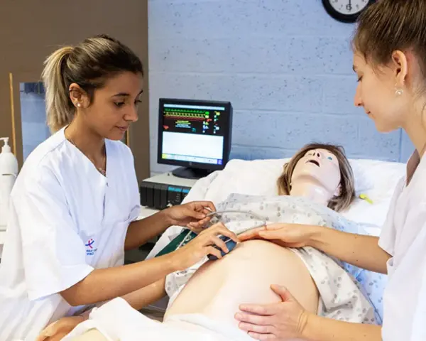 Étudiantes en sage-femme en Belgique pratiquant sur un mannequin de grossesse.