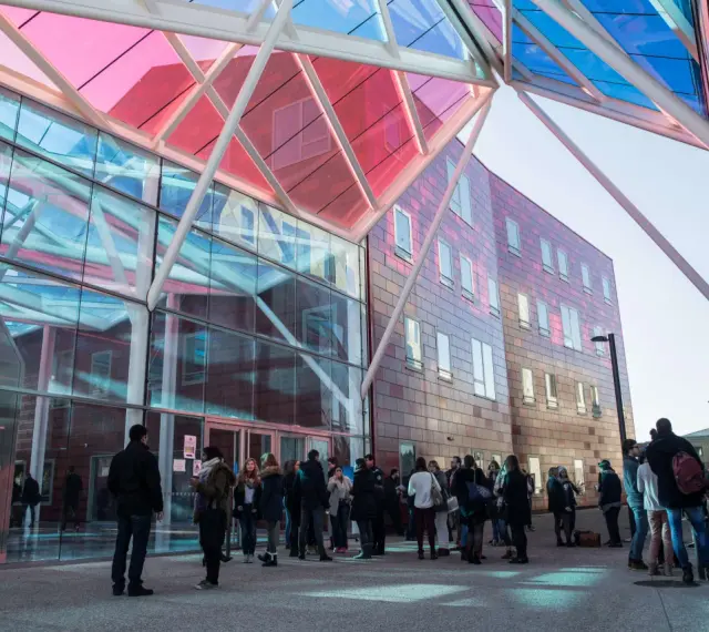 Étudiants devant le bâtiment moderne de l'ICN Business School, avec sa façade vitrée et son toit coloré.