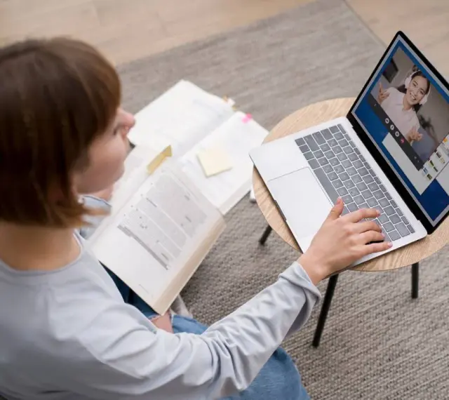 Étudiante en licence neurosciences à distance, elle étudie sur son ordinateur portable et des livres ouverts.