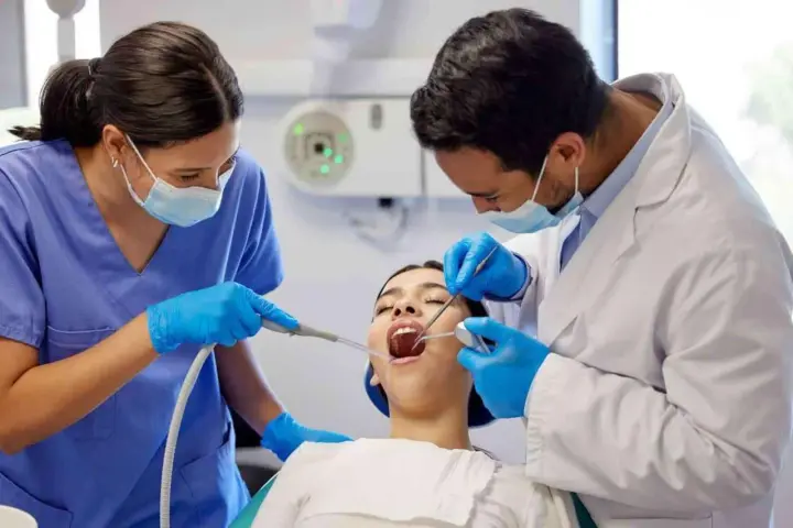 Dentiste et assistante examinant une patiente. Le coût d'une étude orthodontiste peut varier.