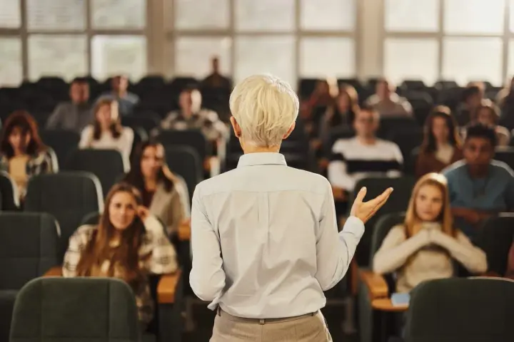 Professeure s'adressant à des étudiants dans un amphithéâtre, un lieu d'apprentissage pour une école de commerce publique gratuite.