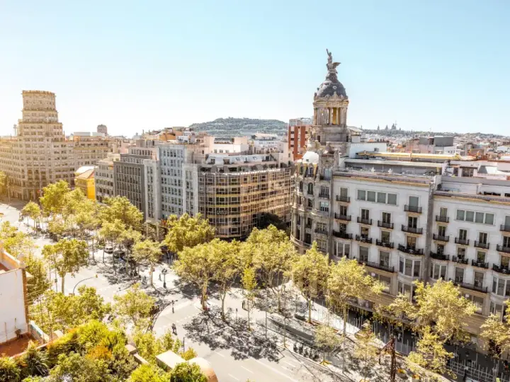 Vue aérienne de Barcelone, ville dynamique qui pourrait figurer dans le classement université espagne. Bâtiments haussmanniens, arbres luxuriants et ciel bleu.