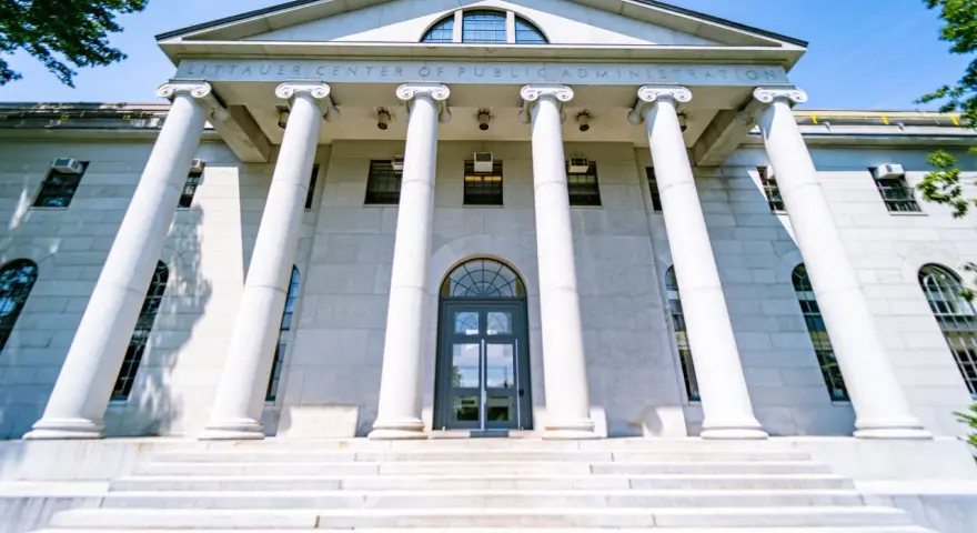 Le Littauer Center of Public Administration, un bâtiment emblématique d'une université américaine connue, se dresse fièrement avec ses colonnes imposantes et son escalier majestueux.