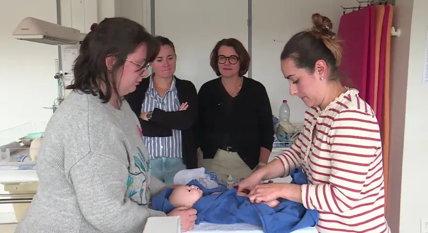Des infirmières pédiatriques en formation observent et pratiquent les soins sur un poupon.