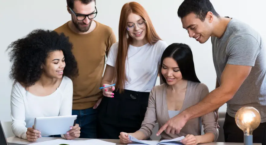 Une équipe diversifiée collabore sur un projet, comme un master moyen orient. Ils étudient des documents et utilisent une tablette.