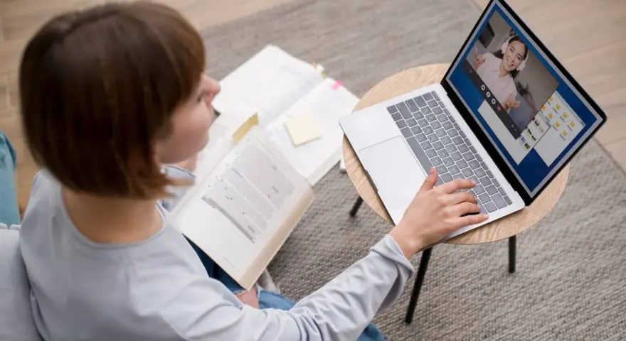 Étudiante en licence neurosciences à distance, elle étudie sur son ordinateur portable et des livres ouverts.