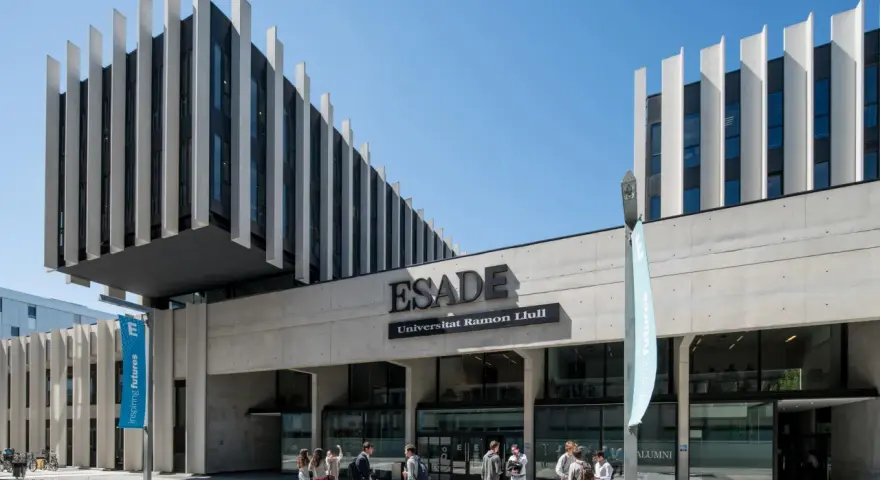 Devant l'ESADE Barcelone, une école reconnue pour son classement, des étudiants discutent sous un ciel bleu.