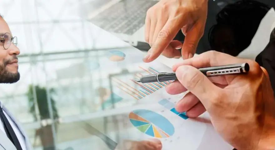 Un homme en costume regarde des graphiques financiers. Des mains analysent des données, suggérant une licence finance à distance.