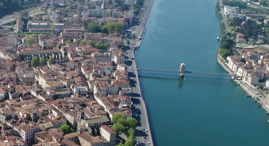 Vue aérienne de la ville de Vienne, traversée par un fleuve et un pont. L'école de Vienne se reflète dans l'eau.
