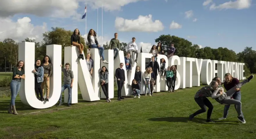 Un groupe d'étudiants pose joyeusement devant les lettres géantes "UNIVERSITY OF TWENTE".