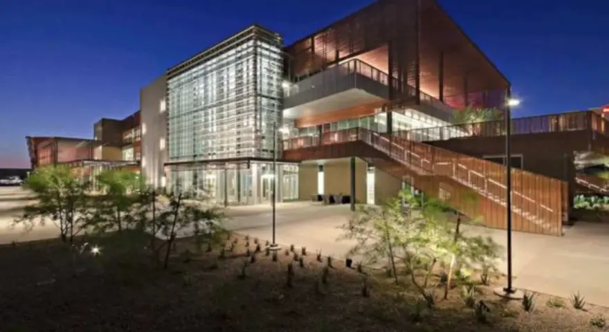 Bâtiment moderne d'un college aux États-Unis, avec une façade vitrée et des escaliers extérieurs en bois, éclairé la nuit.
