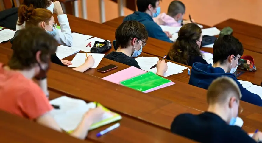 Étudiants masqués en classe, concentrés sur leurs notes. Un aperçu du coût de la vie au Danemark, où l'éducation est une priorité.