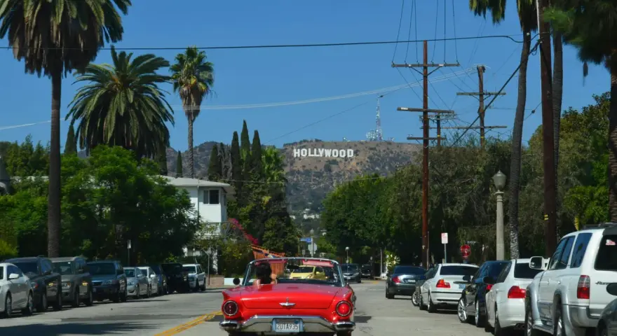 Voiture rouge décapotable, palmiers, panneau Hollywood. Le cout de la vie USA, un rêve pour certains, une réalité coûteuse pour d'autres.