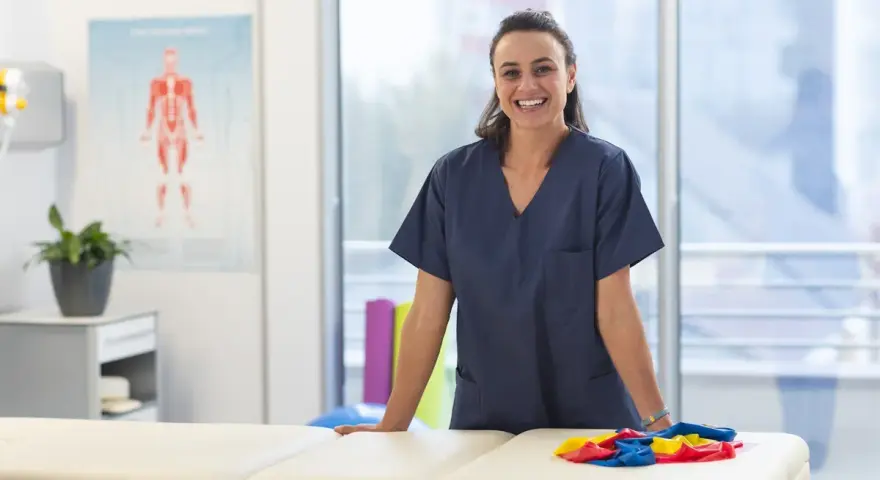 Une kinésithérapeute souriante dans sa salle de soins, prête à accueillir ses patients. L'école kine Saragosse forme des professionnels de santé.