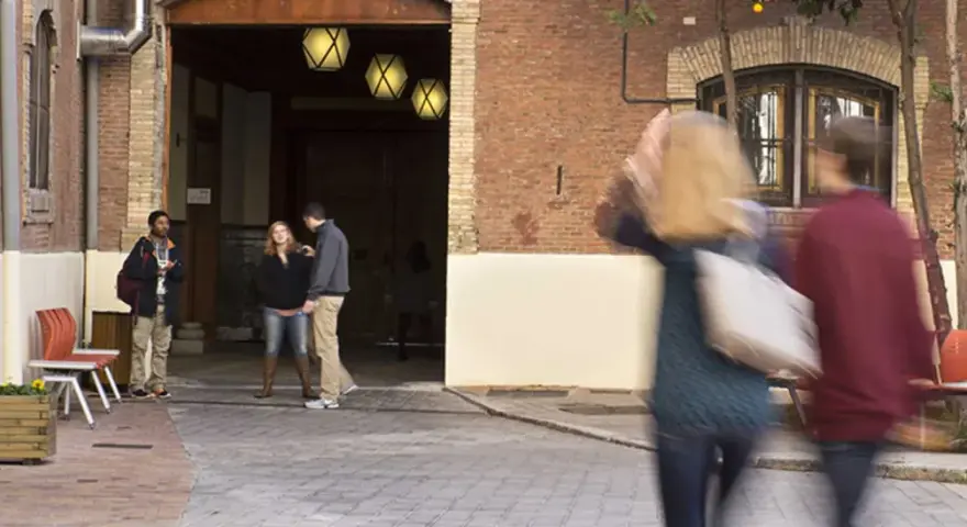 Des étudiants discutent dans une cour d'une vieille bâtisse, un lieu qui pourrait être un master à Madrid.