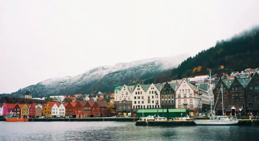 Vue du port de Bergen, Norvège, avec ses maisons colorées et ses montagnes enneigées. Un aperçu du coût de la vie en Norvège.