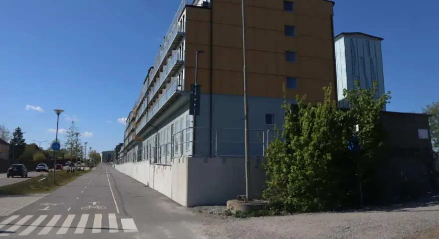Immeuble moderne avec balcons vitrés, idéal pour le logement étudiant à Stockholm. Une piste cyclable longe le bâtiment.