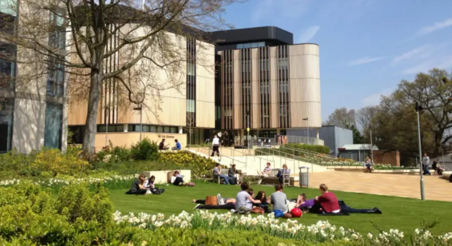 Étudiants profitant du soleil sur la pelouse devant le bâtiment de la **université de Southampton**.